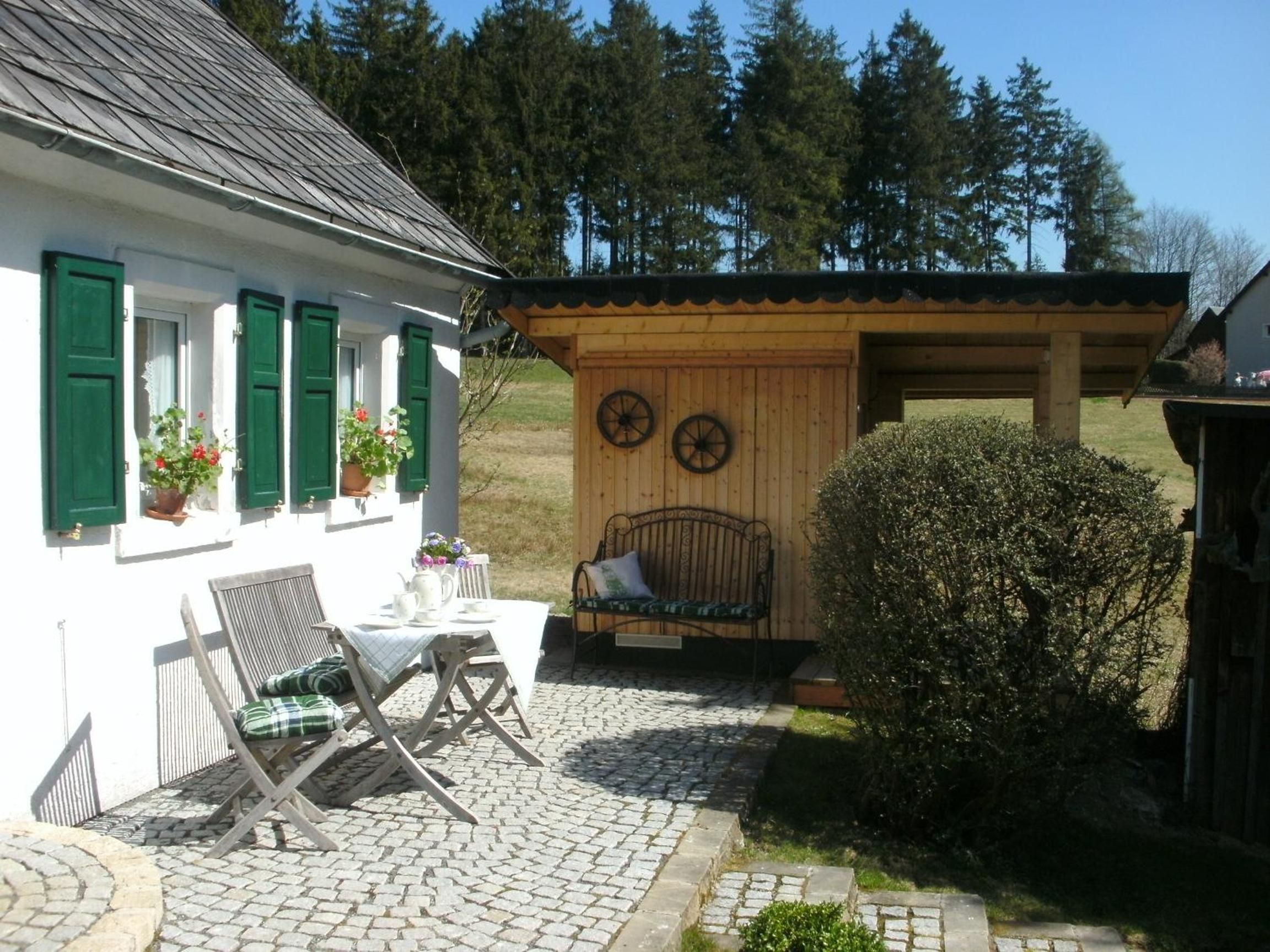 Et hyggeligt udendørs siddeområde med et bord, stole og en bænk.