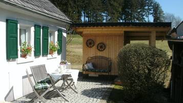 Et hyggeligt udendørs siddeområde med et bord, stole og en bænk.