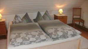 Un lit double avec une literie à motifs floraux, deux tables de chevet avec des lampes et une chaise en bois.
