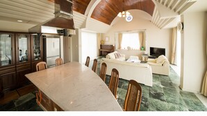 A spacious living area with a large dining table, comfortable seating, and a cozy fireplace. - Seaside Tellme Ishigakizima (Ishigaki)
