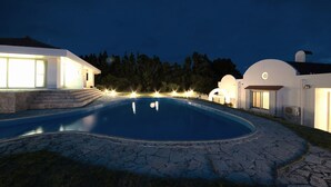 A modern house with a swimming pool, surrounded by a stone deck and well-lit by exterior lights. - Seaside Tellme Ishigakizima (Ishigaki)