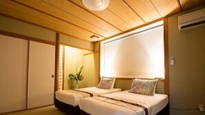 A traditional Japanese-style room with tatami flooring, a low wooden ceiling, and a sliding door. There are two beds with white bedding and colorful pillows. - Seaside Tellme Ishigakizima (Ishigaki)