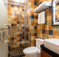A bathroom with a glass shower enclosure, a toilet, and a sink with a black countertop.