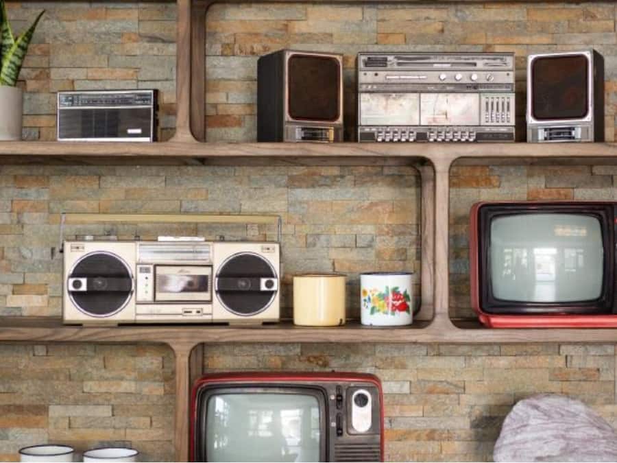 Una pared con varios aparatos electrónicos antiguos y una planta en maceta.