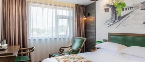 Une chambre d’hôtel avec un lit, un bureau, une chaise et un tableau au mur.