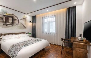 Een hotelkamer met een bed, een bureau met televisie en een groot raam met gordijnen.