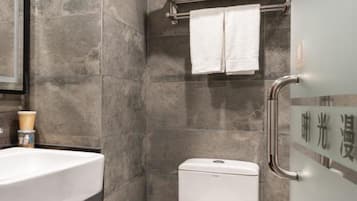 A modern bathroom with a white sink, a toilet, and a shower area.