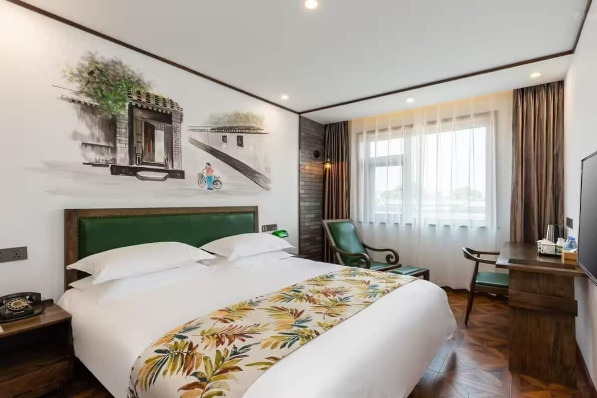 Een hotelkamer met een groot bed, een bureau met stoel, een televisie en een raam met gordijnen.