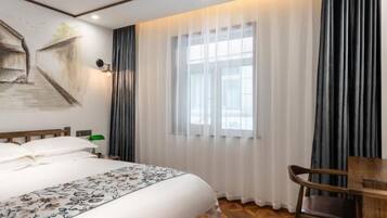 A hotel room with a large bed, a wooden desk, and a chair.