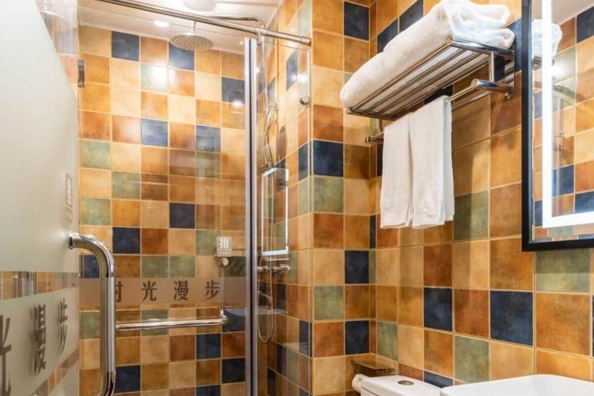 Une salle de bain dotée d’une douche à parois de verre, de toilettes blanches et d’un lavabo avec un plan de travail noir.