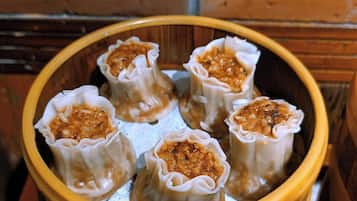 Un tazón de madera con varios dumplings rellenos de carne picada y vegetales.
