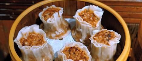 A wooden bowl containing several dumplings with a filling that appears to be a mixture of minced meat and vegetables.