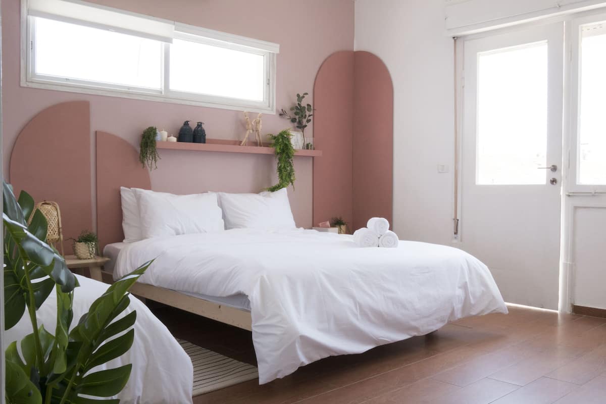 A bedroom with a bed, a bedside table, a window, and a door.
