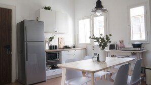 Una cocina moderna con refrigerador, microondas y estufa. Hay una mesa de comedor con sillas y un florero con flores.