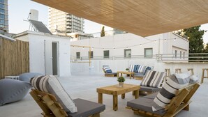 Un espacio al aire libre con sillones de madera, una mesita y una pérgola.