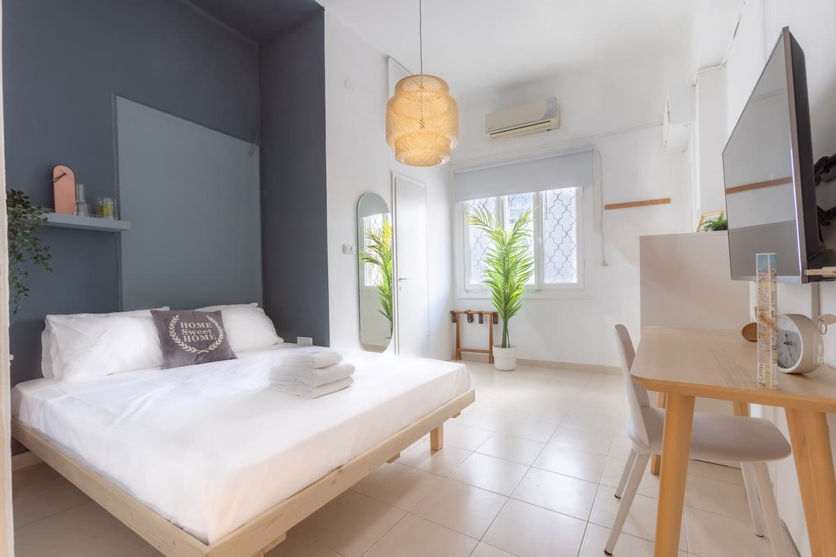 A modern bedroom with a bed, bedside table, and a large mirror.