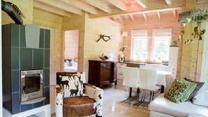Ein gemütliches Blockhaus-Interieur mit Kamin, Essbereich und Wohnzimmer mit einer Couch.