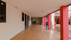Un pasillo largo y estrecho con piso de baldosas y columnas estructurales rojas.