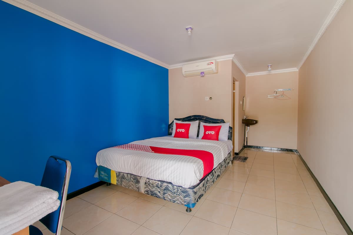 Una habitación de hotel con cama, una silla y baño.
