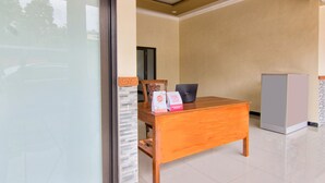 A hotel room with a wooden desk, a laptop, and a refrigerator.