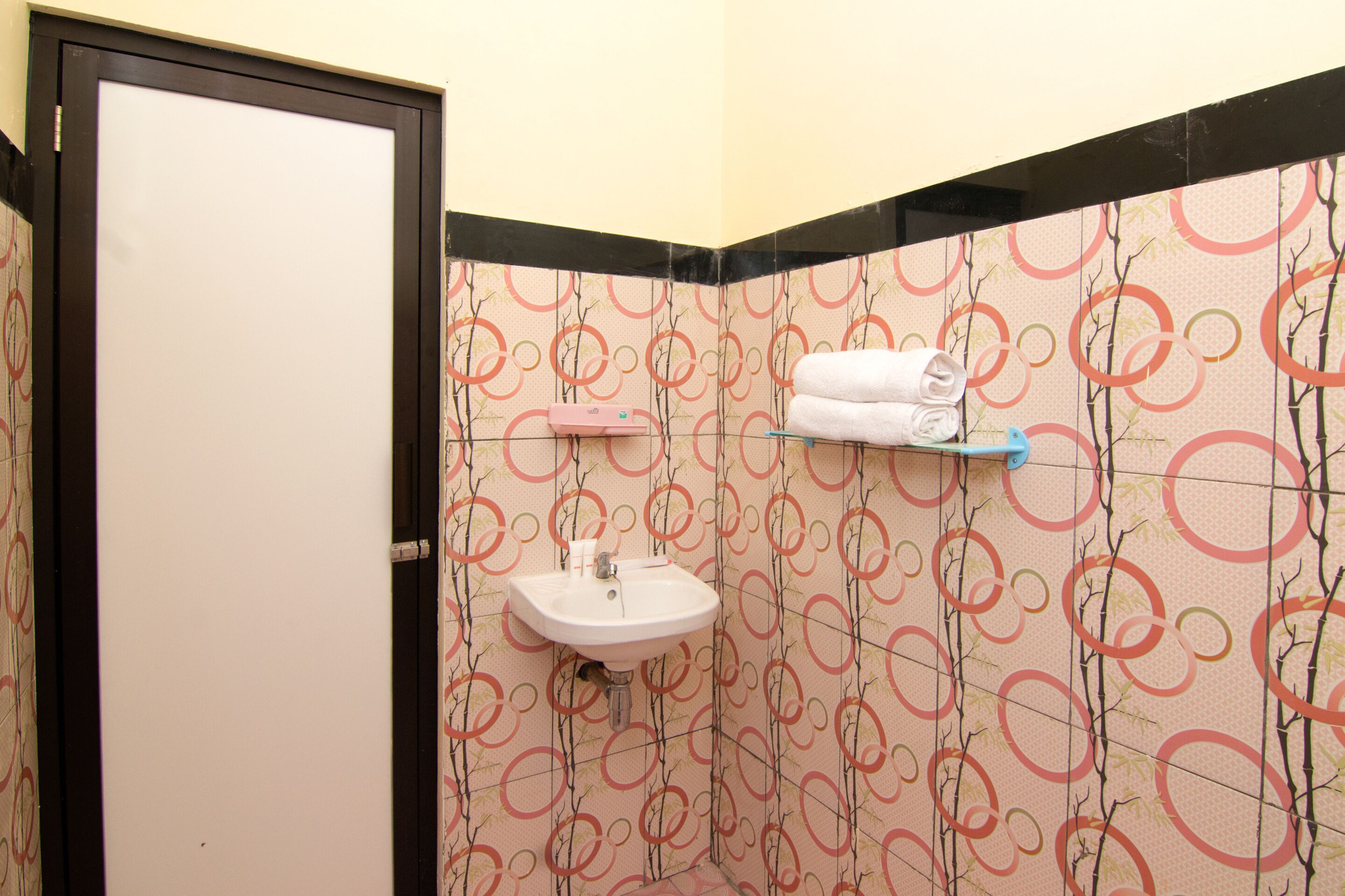 A bathroom with a white sink, a towel rack, and a patterned wall.