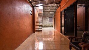 A corridor with a tiled floor, a staircase, and a leather chair.