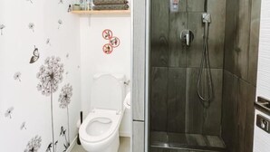 A bathroom with a toilet, shower, and a shelf with toiletries. - Studio Wood Nature & Confort 3* Wifi+Parking (Laveyron)