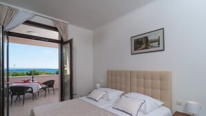 Habitación de hotel con cama, mesita de noche, mesa con sillas y balcón con mesa y sillas.