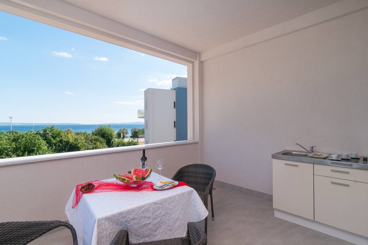 Un balcón con una mesa para dos, vista al mar y una kitchenette.