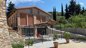 A stone building with a brick facade, a covered patio area with outdoor furniture, and potted plants.