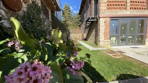 A garden with pink flowers and a brick building with a glass door. - Super-modern studio on the hills of Florence, Tuscany  (BAGNO A RIPOLI)