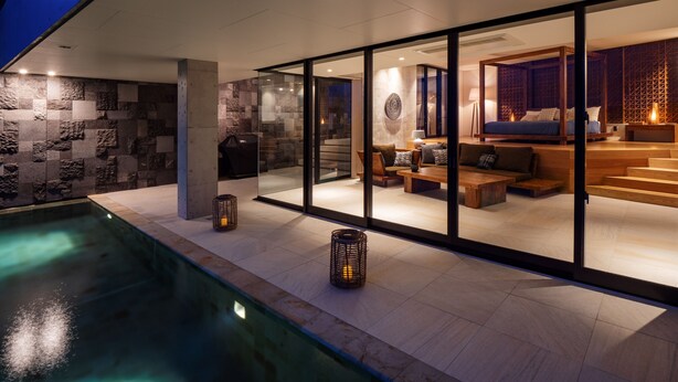 A modern house with a glass-enclosed living area, a pool, and stone walls. - Leceb Sesoko Villa (Motobu)