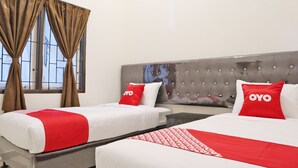 Ein Hotelzimmer mit zwei Betten, jeweils mit rotem und weißem Bettbezug und Kissen, einem gepolsterten Kopfteil und einem Fenster mit Vorhängen.