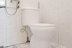 Een toilet met tank en zitting, verbonden met een douche slang.