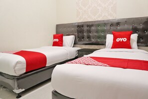 Twee bedden met wit en rood beddengoed, een gestuwd hoofdeinde en een behang met patroon.