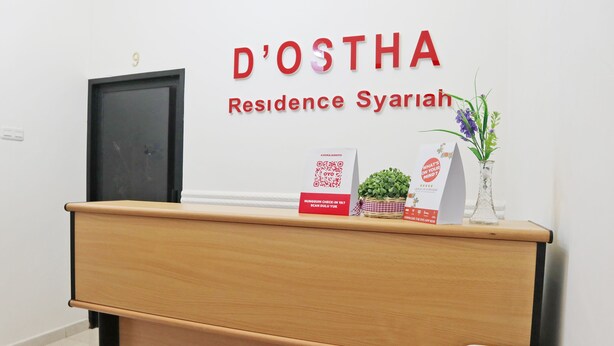 Ein Empfangsschalter mit Holzausstattung, eine Tür mit der Aufschrift '9' und ein Schild, das 'D'OSTHA Residence Syariah' zeigt.