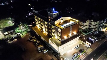 Un hotel de varios pisos con ventanas iluminadas y una terraza en la azotea.