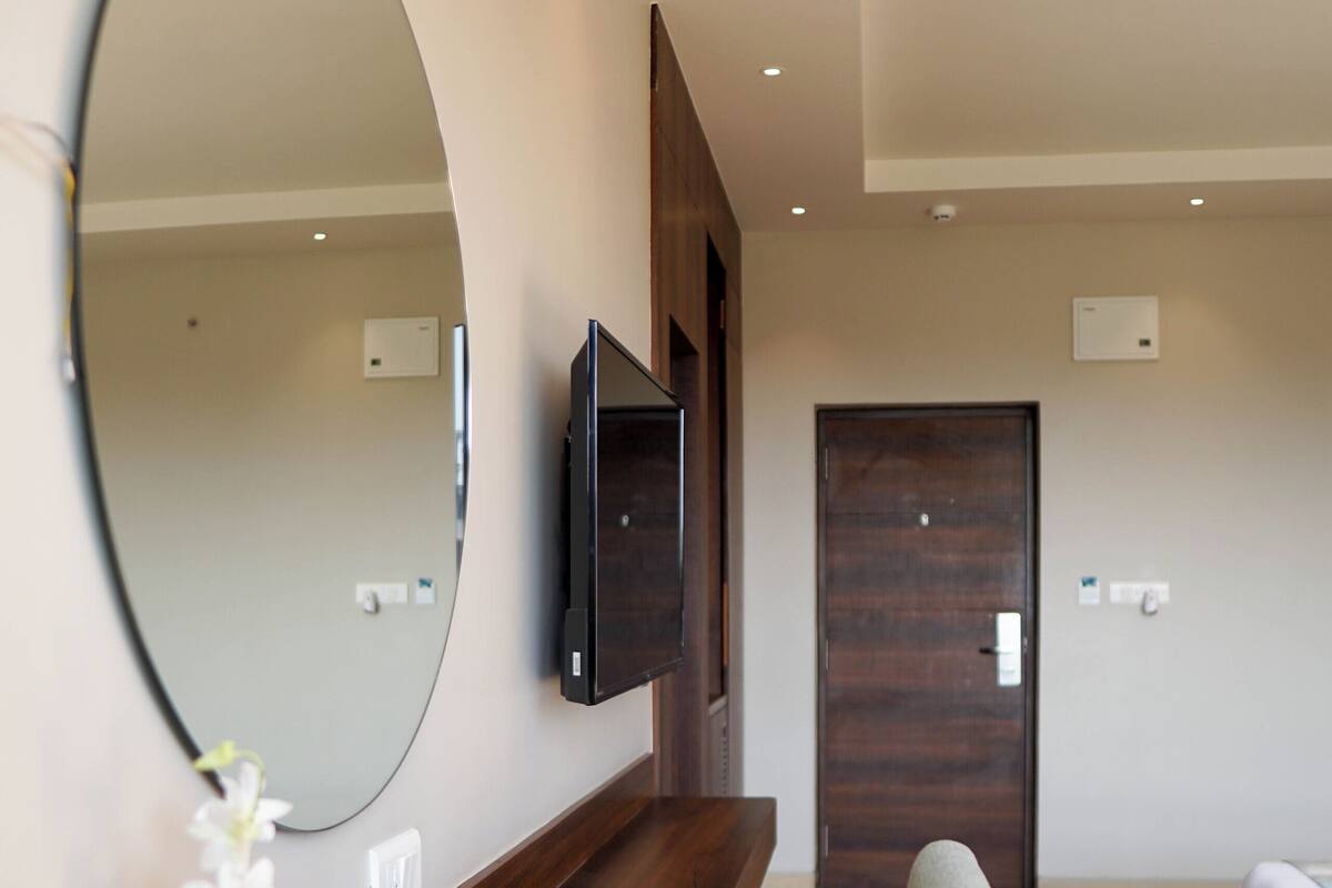 A modern living room with a wooden coffee table, a large mirror, and a mounted TV.