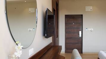 A modern living room with a wooden coffee table, a large mirror, and a mounted TV.