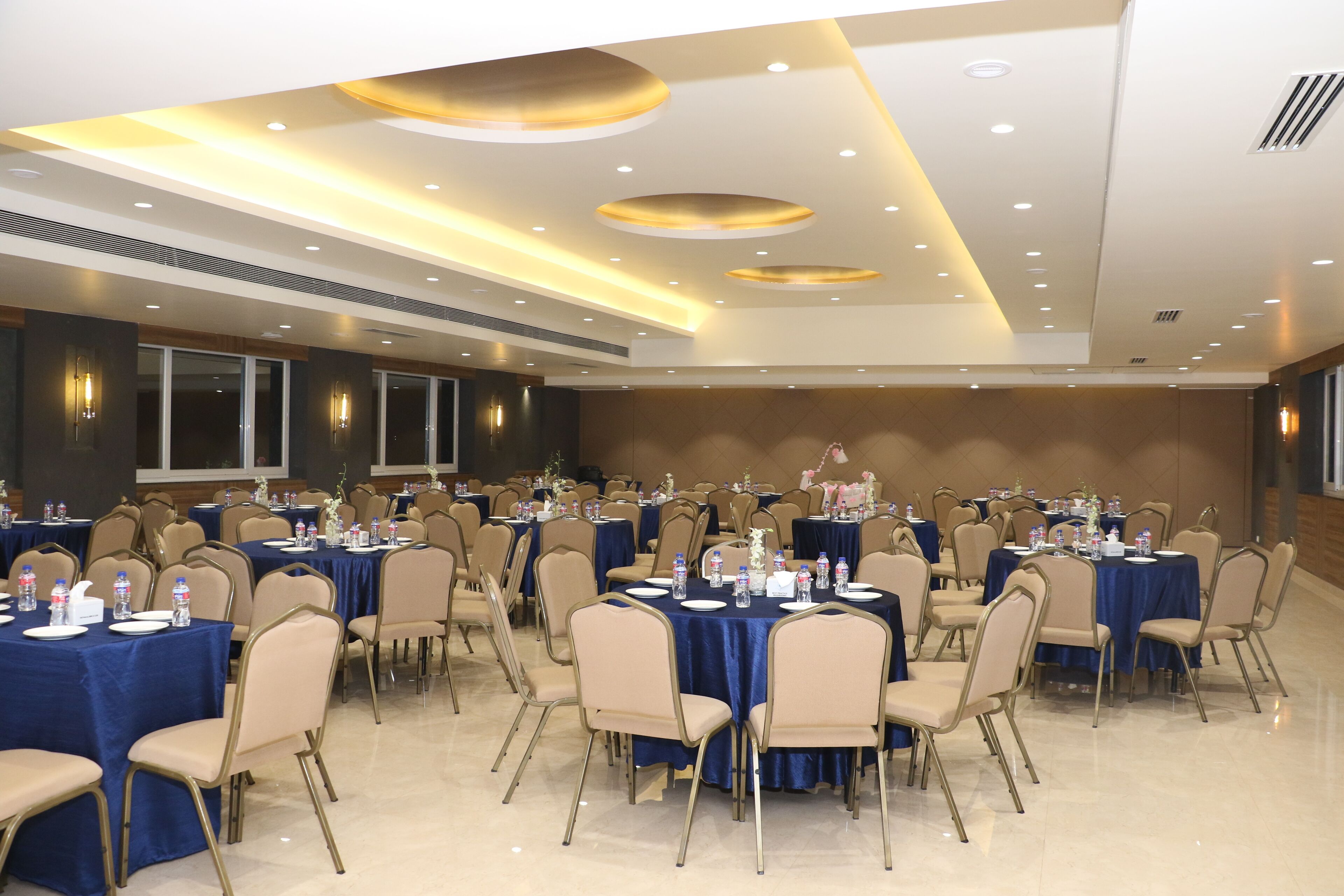 Une salle de conférence dotée de plusieurs tables et chaises, ainsi que de bouteilles d’eau et de plaques nominatives.