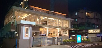 Un hotel moderno con fachada de vidrio, una recepción visible y un letrero que dice Hotel Cosmos.