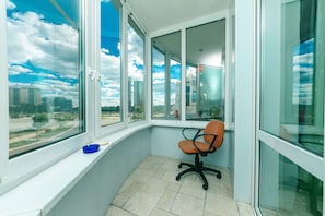 A corner office with a large window, a chair, and a small blue tray on the windowsill.