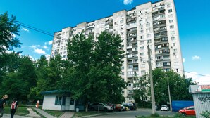 A multi-story residential building with balconies, a small adjacent structure, and parked cars. - Apartment on Cheliabinska 19 (Kyiv)