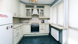 A kitchen with white cabinets, a stove, a microwave, and a refrigerator. - Apartment on Cheliabinska 19 (Kyiv)