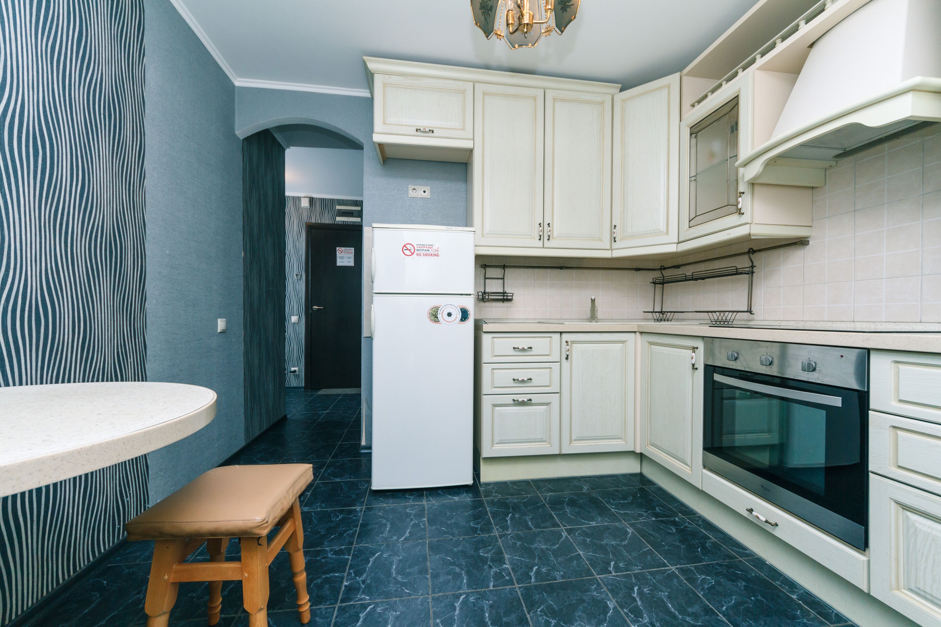 Eine Küche mit weißen Schränken, einem eingebauten Backofen und einem Kühlschrank.