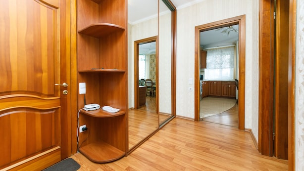 A room with wooden flooring, a mirror, and a wooden wardrobe. - Comfortable apartment on the left bank (Kyiv)