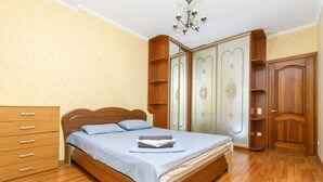 A bedroom with a wooden bed, a dresser, and a wardrobe with decorative panels. - Comfortable apartment on the left bank (Kyiv)
