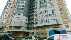 A high-rise residential building with multiple balconies and a parking area in front. - Comfortable apartment on the left bank (Kyiv)