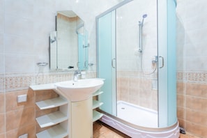 A bathroom with a sink, mirror, and shower.