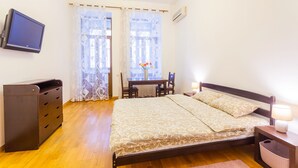 Een slaapkamer met een bed, een bureau, een stoel, een televisie en een dressoir.